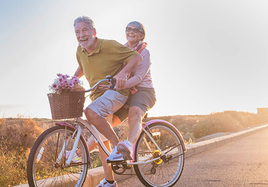 Old couple riding bicycle smiling